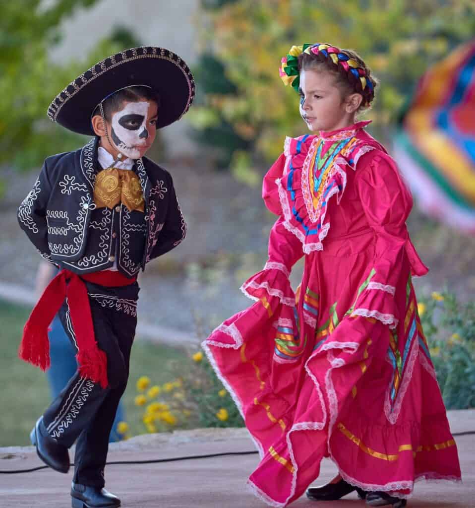 Young girl and boy in traditional Mexican dress dancing