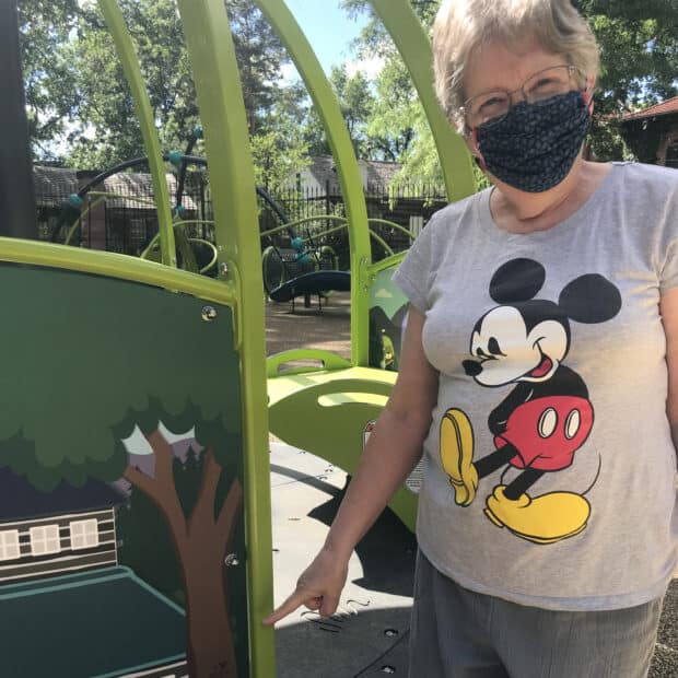 Woman in a mask pointing to the design of a merry-go-round