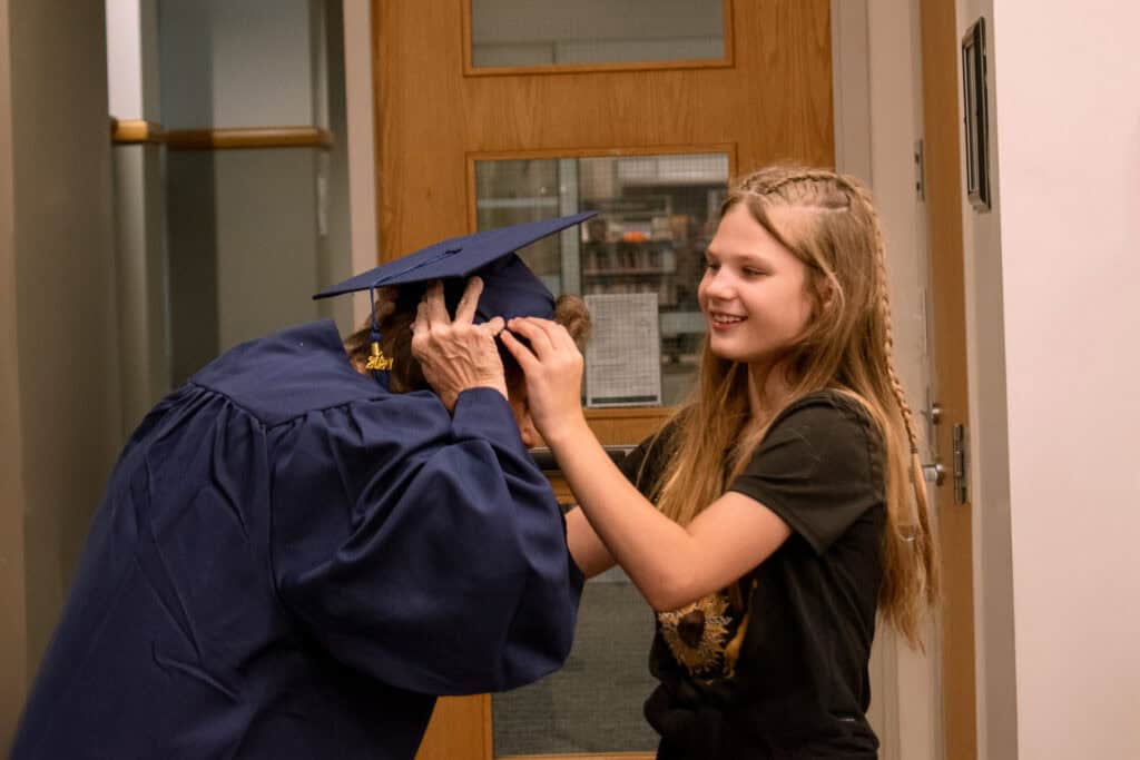 granddaughter placing a graduation cap on her grandmother