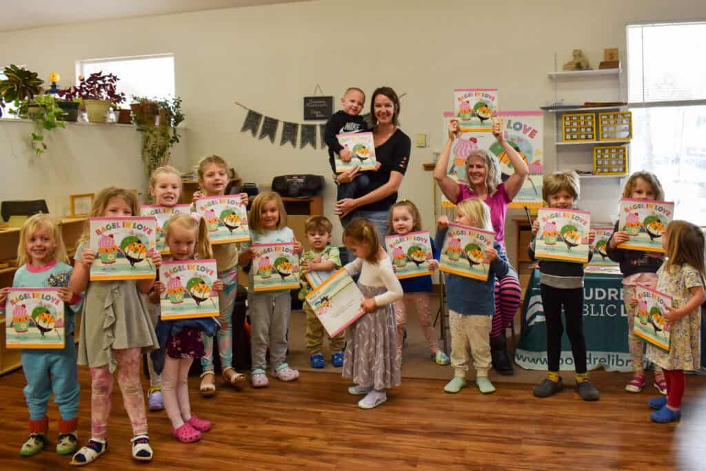 preschool children and their teacher holding up books for a photo