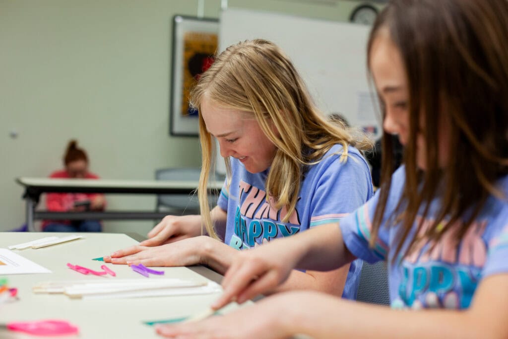 Two young girls crafting in a library