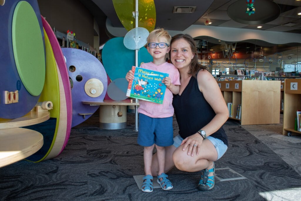 A woman and a child pose for a photo in a library