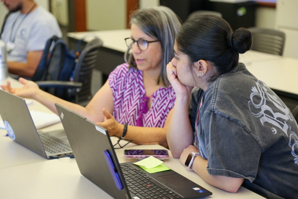 two women in front of computers talking