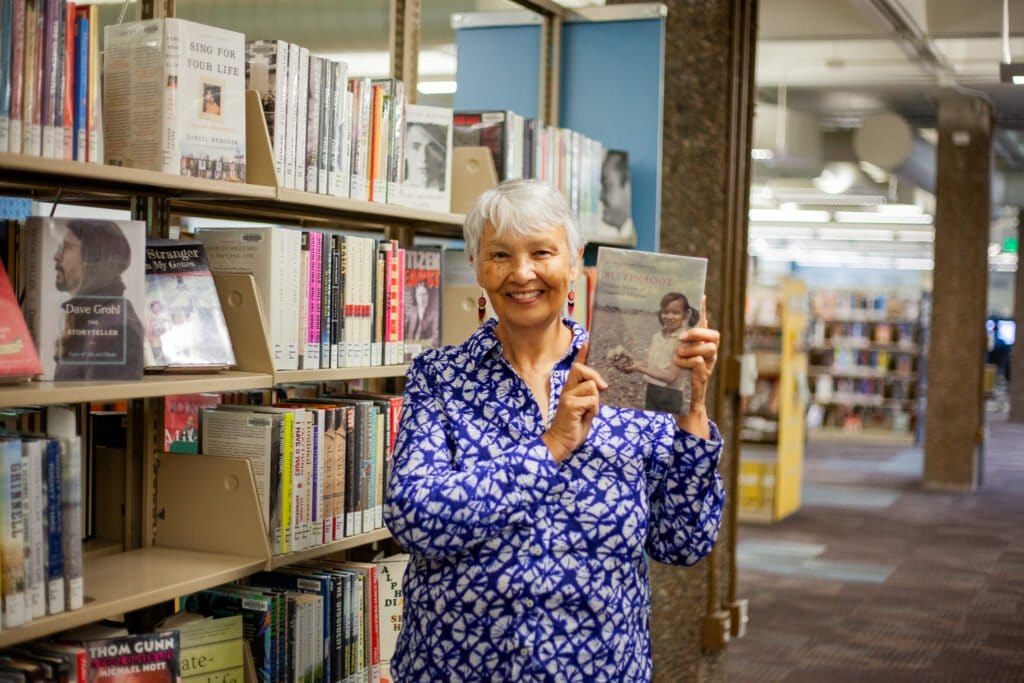 author holding up the copy of her book in the library