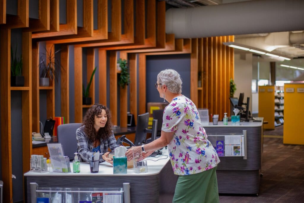 woman getting books from an employee at a library