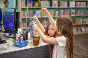 young girls interacting at a library desk