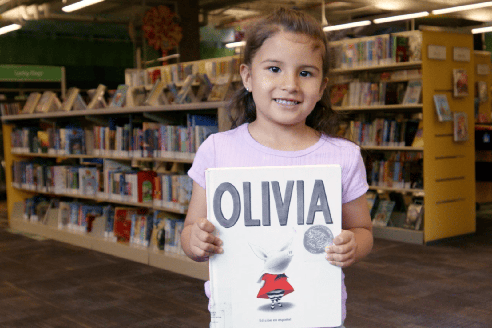young girl smiling and holding a book