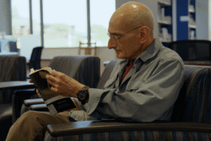 man reading a book in a chair at a library