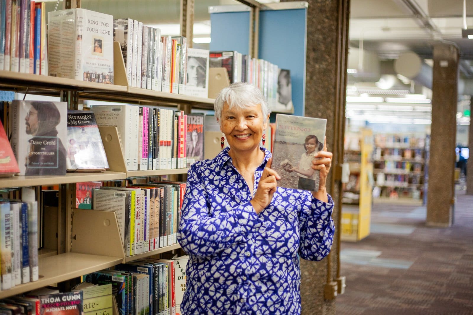 woman holding up a book in a library