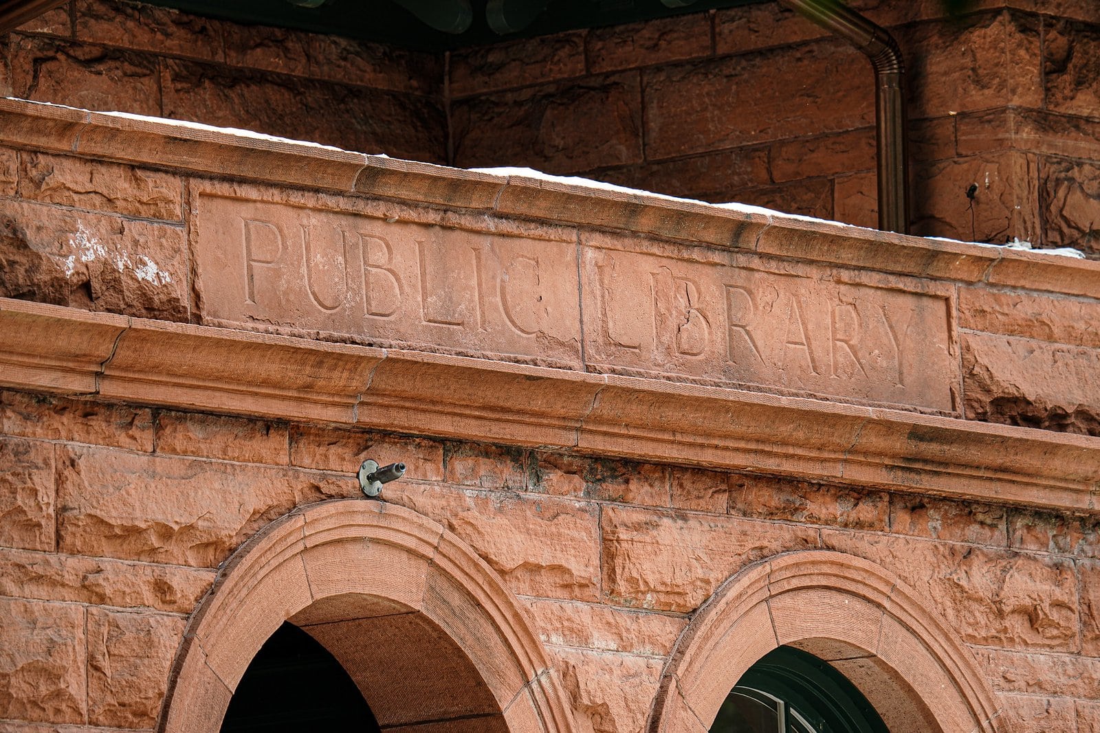 the words public library carved into the exterior of a red sandstone building