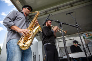 a man playing the saxophone next to a man playing the trumpet on a stage
