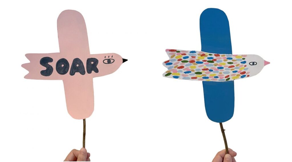 manos sosteniendo pájaros de papel de colores