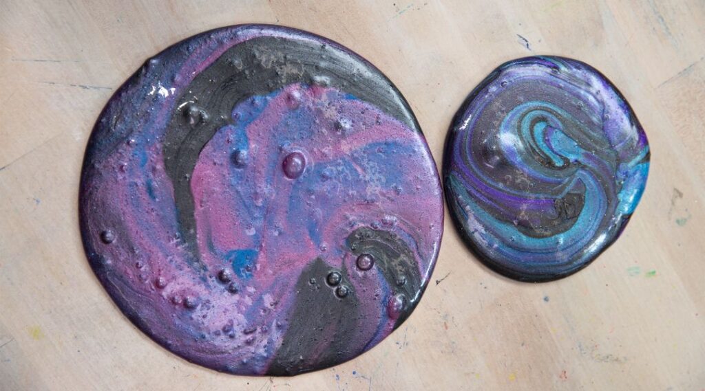 dos charcos de baba de color púrpura, negro y azul sobre una mesa