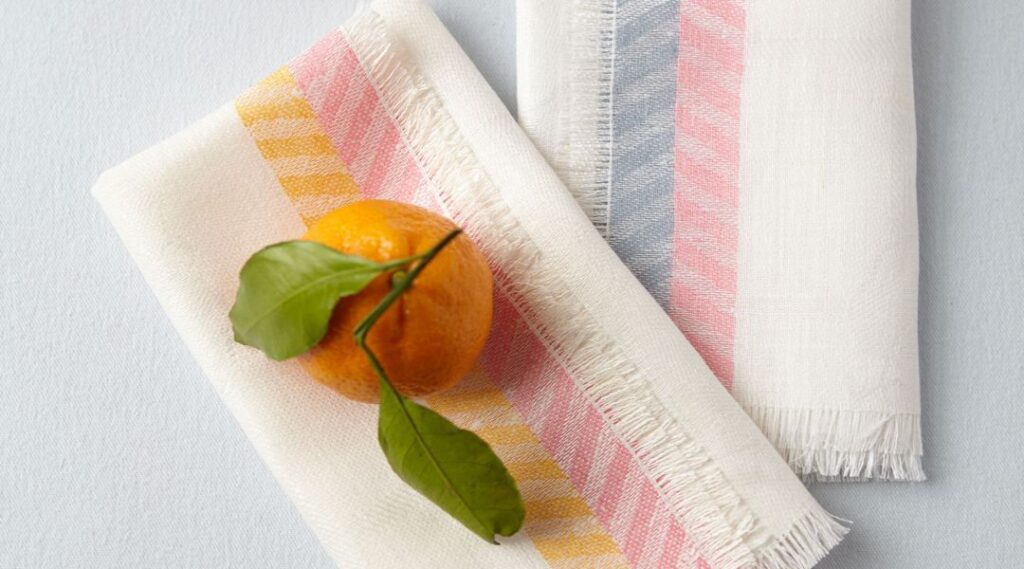 una naranja sobre servilletas de colores pastel puestas planas sobre una mesa