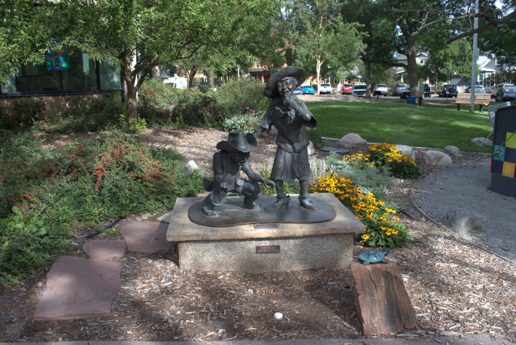 Bronze statue of two children titled "diversions" in Library Park.